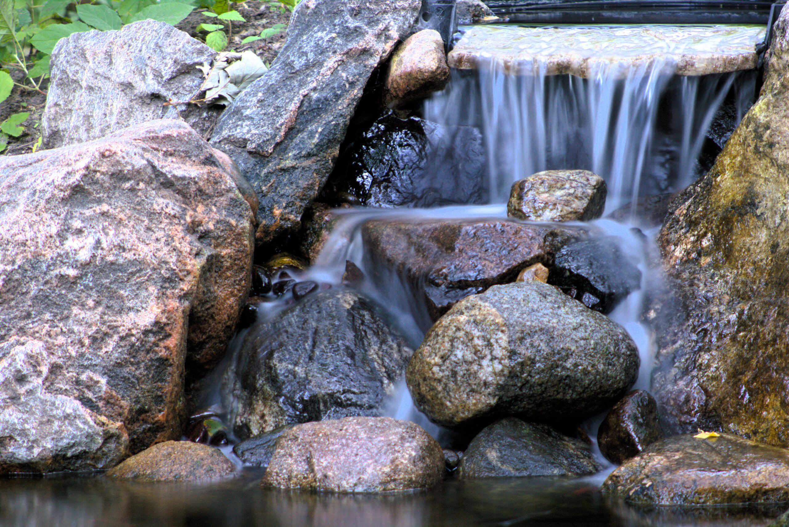 Natural stone waterfall in woodland pond with Aquascape BioFalls system in Chaska, Minnesota