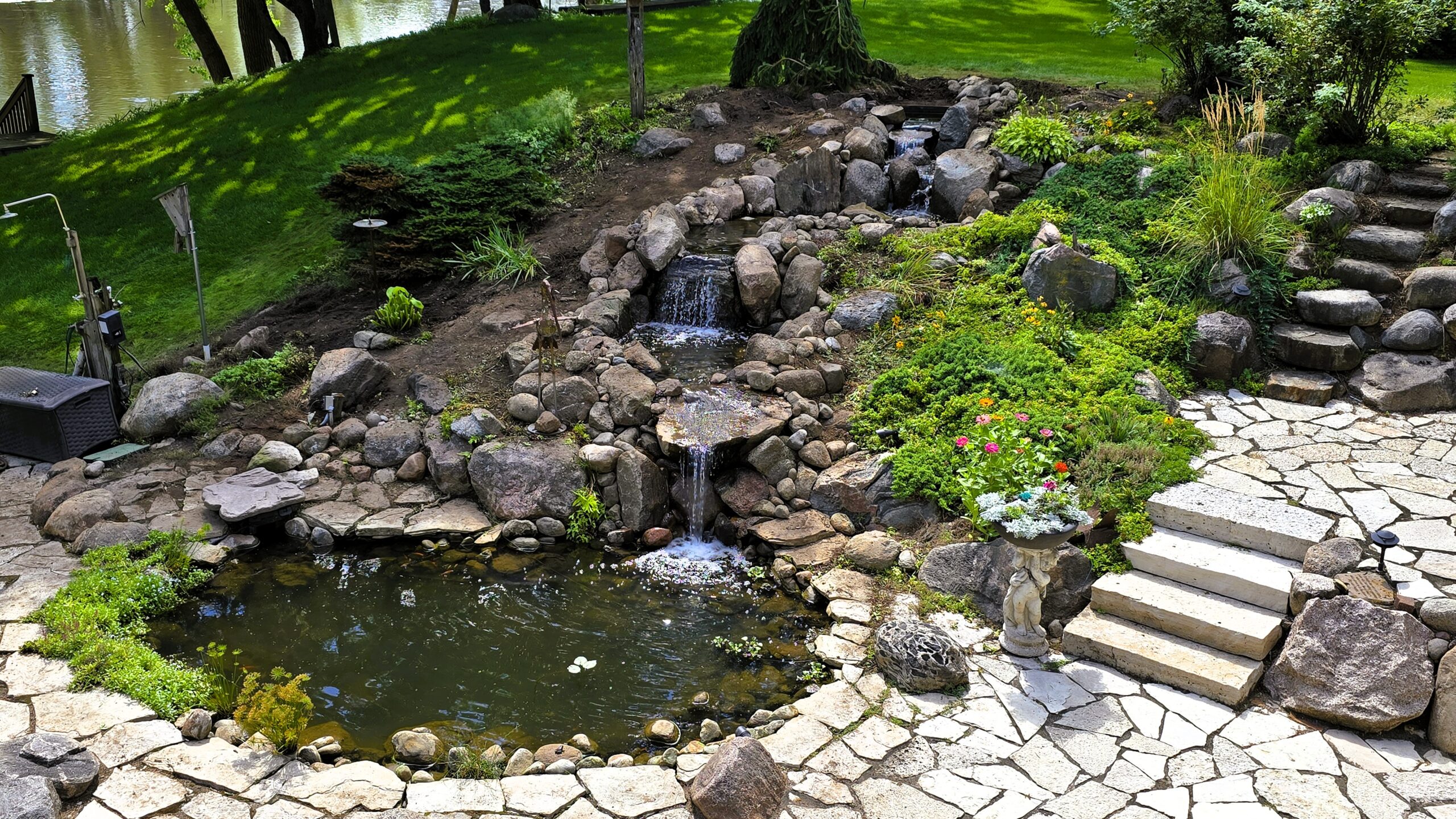 20250819_145128 Rebuilt 35-foot backyard stream in Elk River, MN featuring natural stone waterfalls, upgraded cascades, existing pond, and professional stream reconstruction.