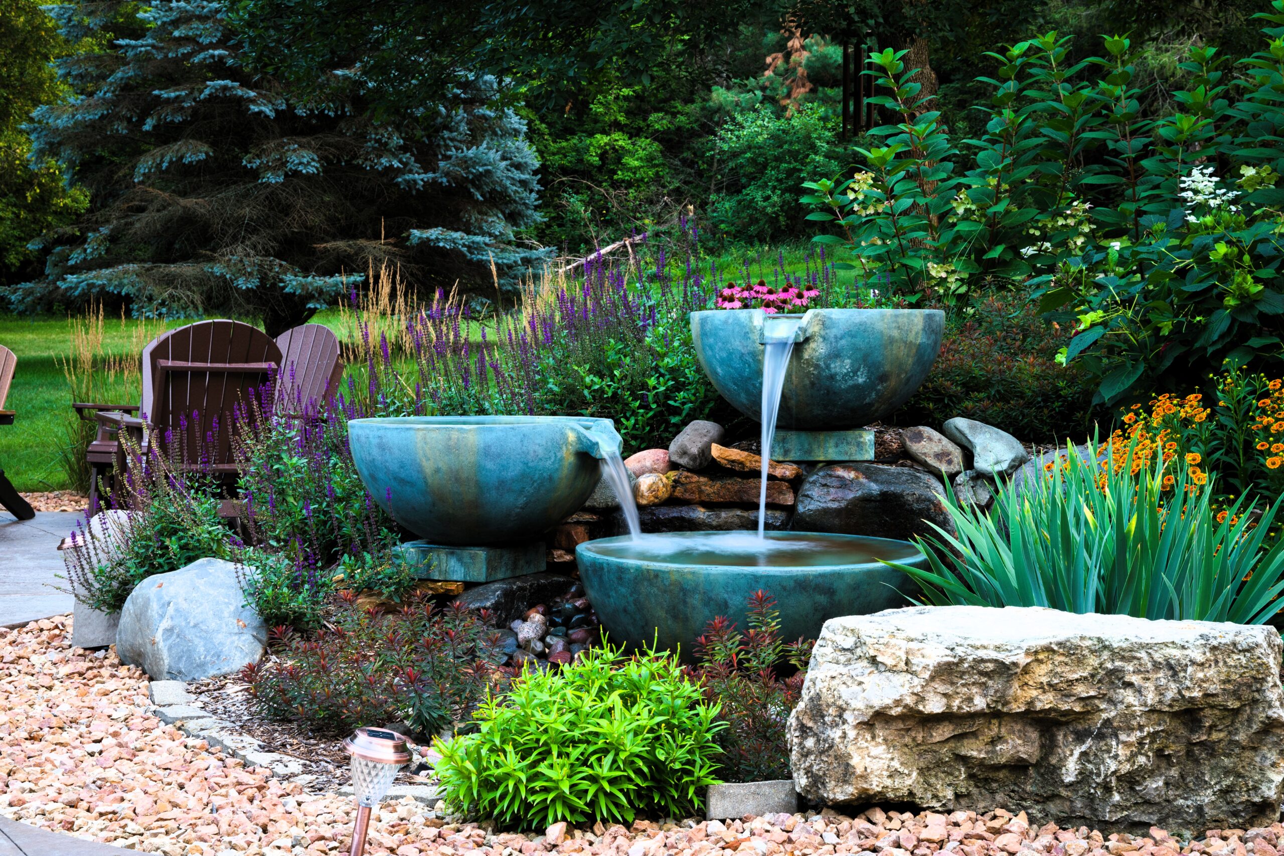 Three-bowl cascade water feature surrounded by colorful landscaping in a backyard in Hudson, Wisconsin.