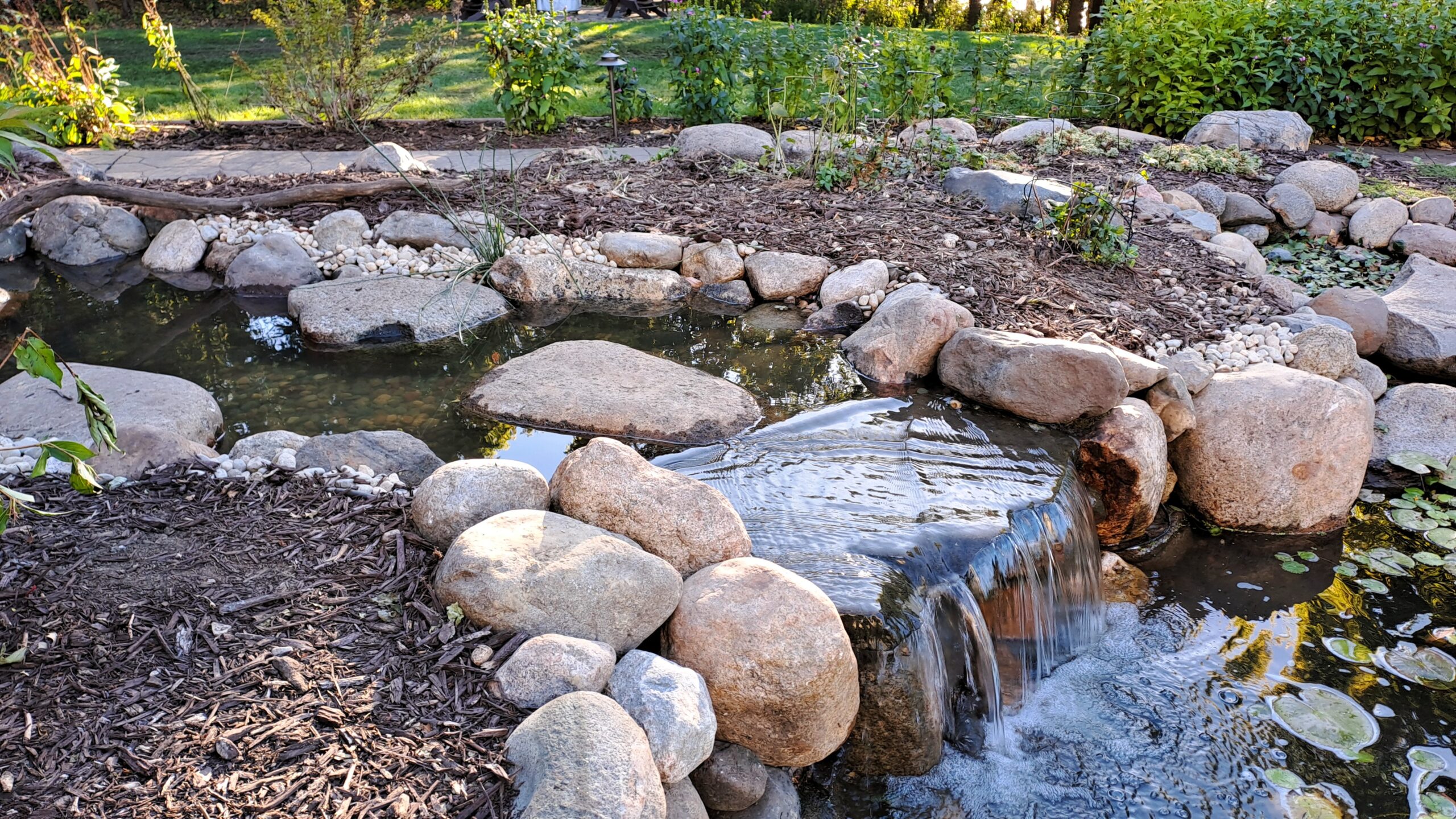 backyard pond stream reconstruction with natural stone waterfall and improved water flow in Minnesota