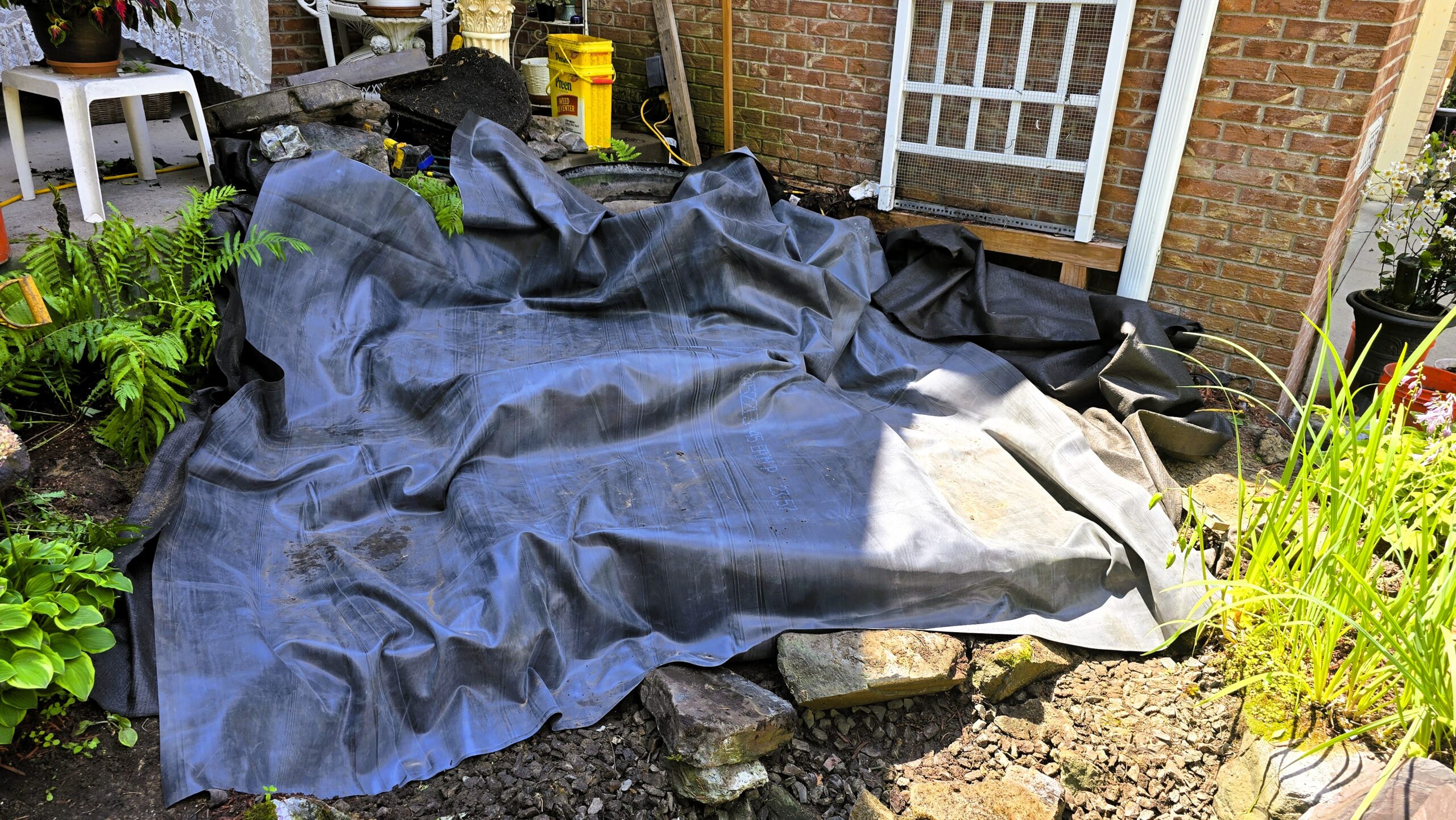 Waterfall rebuild process with new liner installation in front yard pond in Blaine, Minnesota