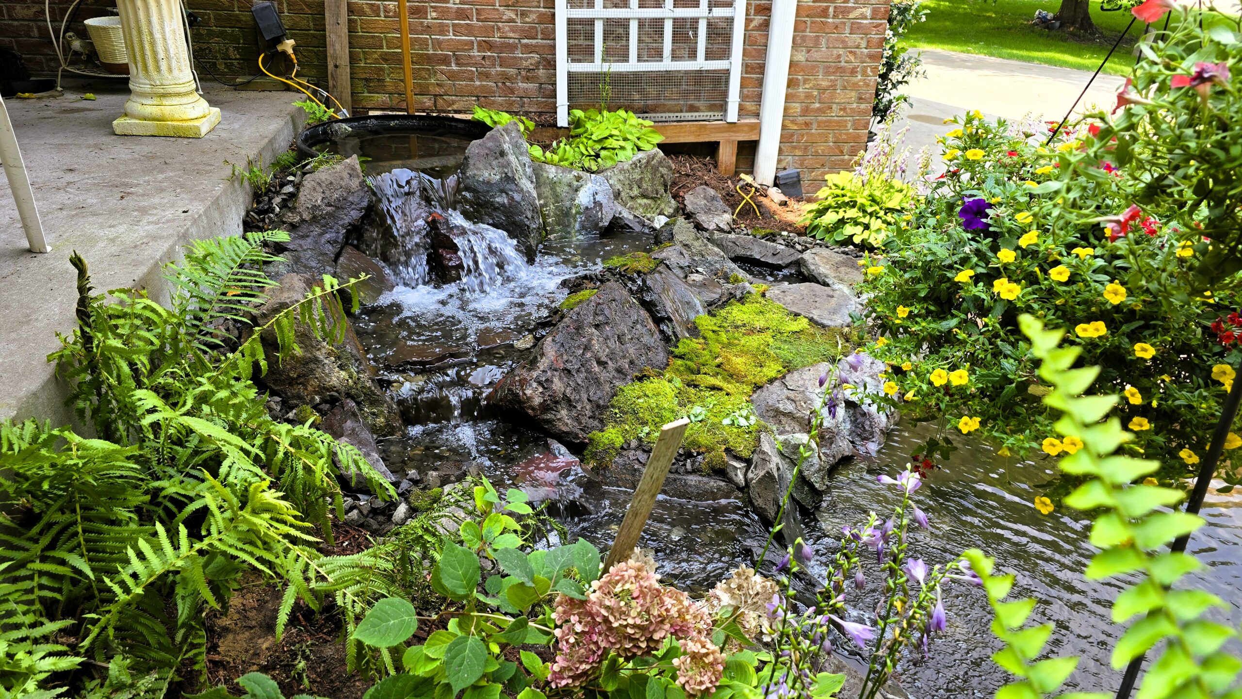 Finished front yard waterfall with Banded Jasper boulders and natural stream flow in Blaine, Minnesota