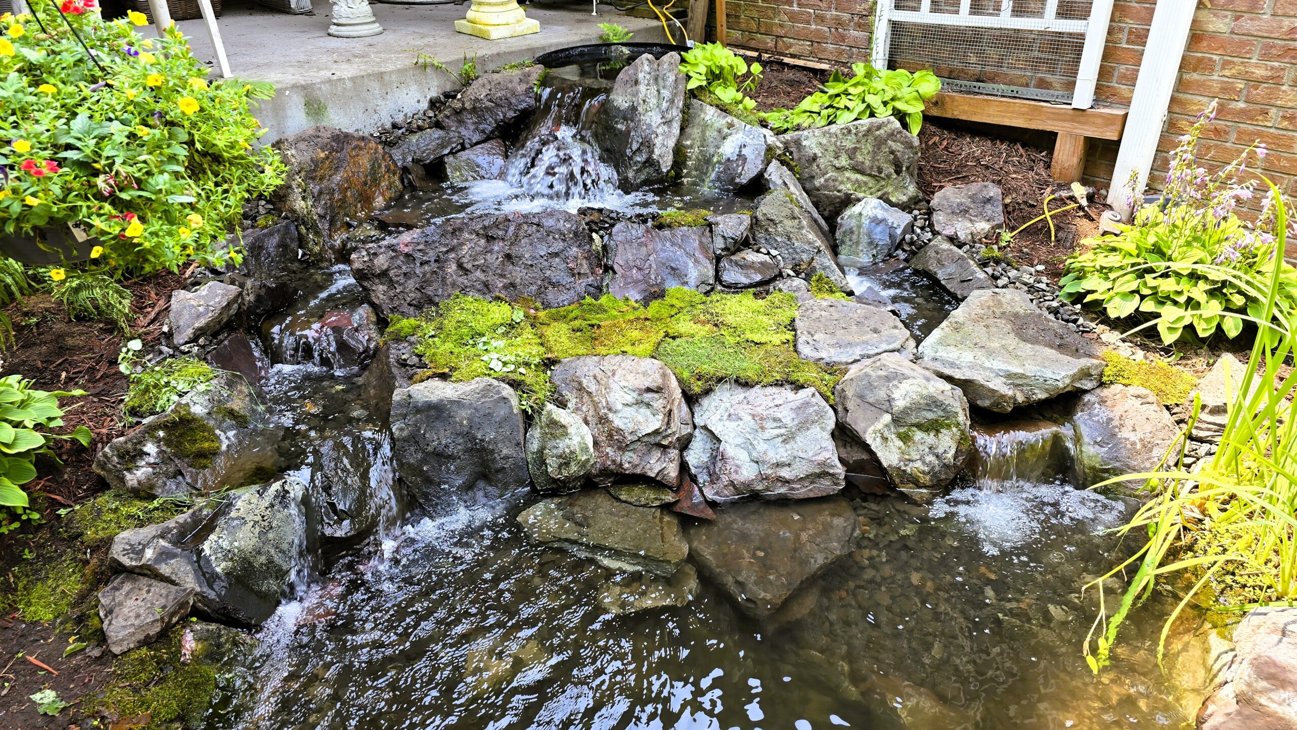Finished front yard waterfall with Banded Jasper boulders and natural stream flow in Blaine, Minnesota