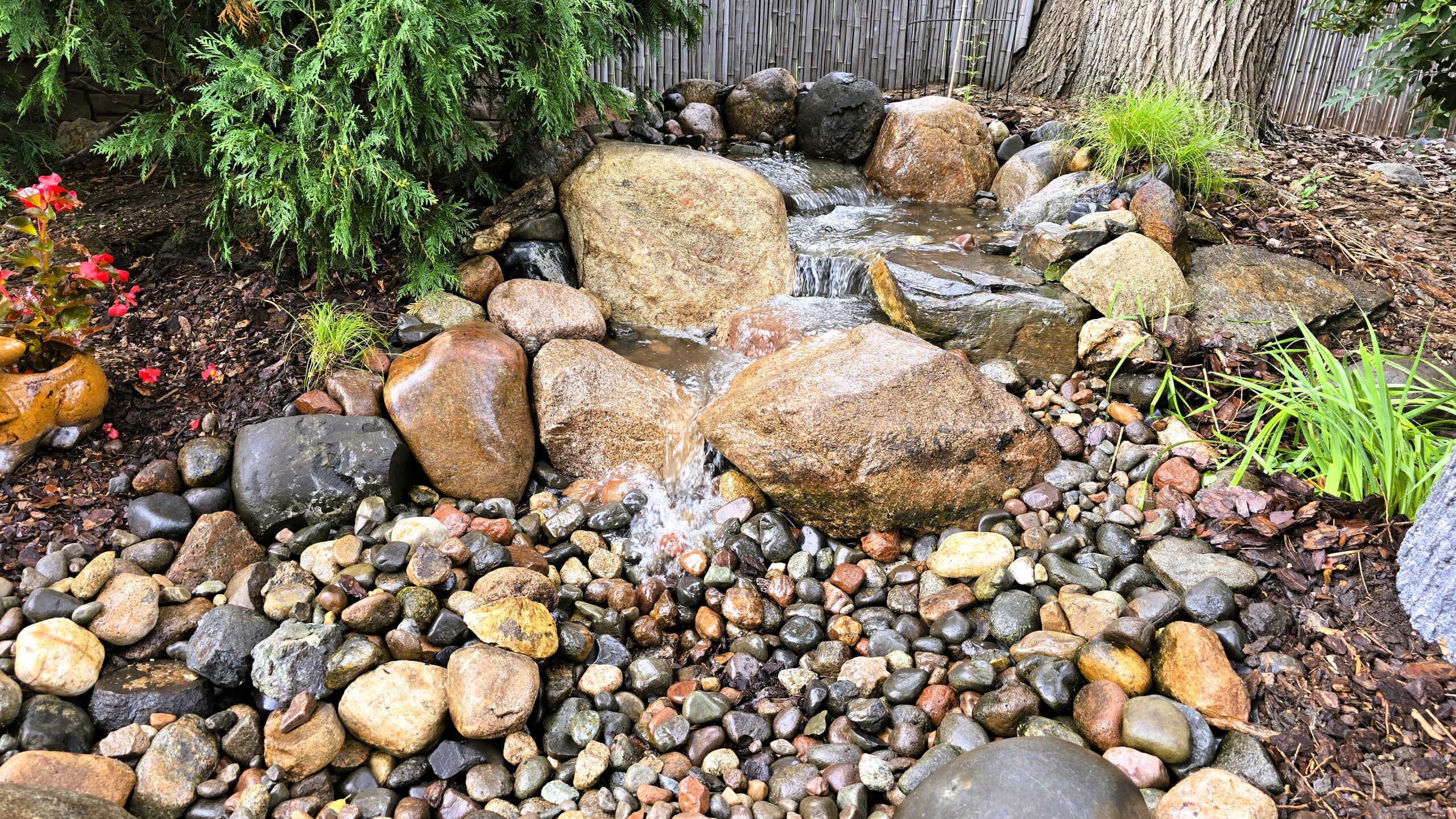Finished pondless waterfall in Hopkins Minnesota with natural stone stream and backyard seating area after rebuild
