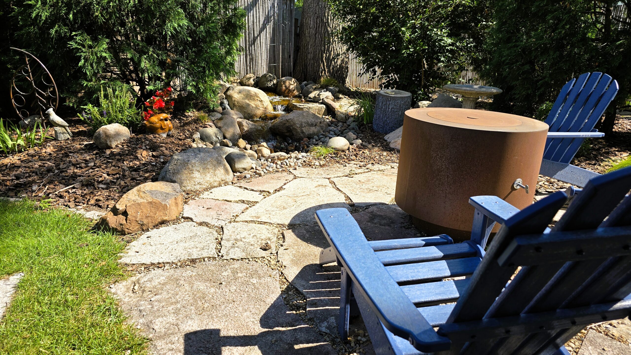 Backyard pondless waterfall in Hopkins Minnesota with natural stone stream and seating area after full rebuild