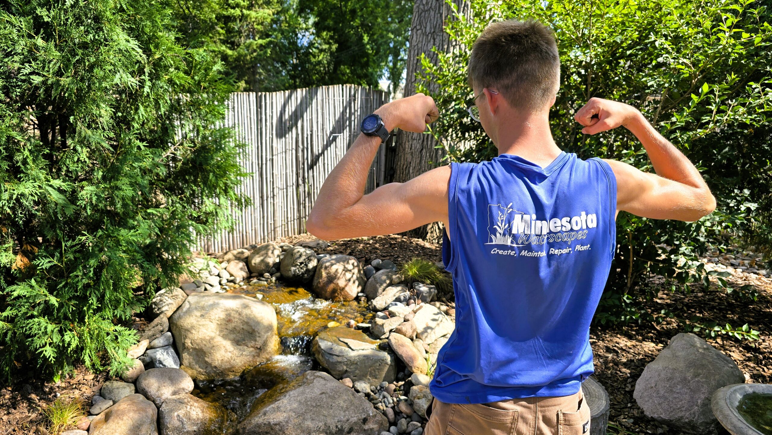 Technician standing near completed pondless waterfall in Hopkins Minnesota showcasing finished rebuild