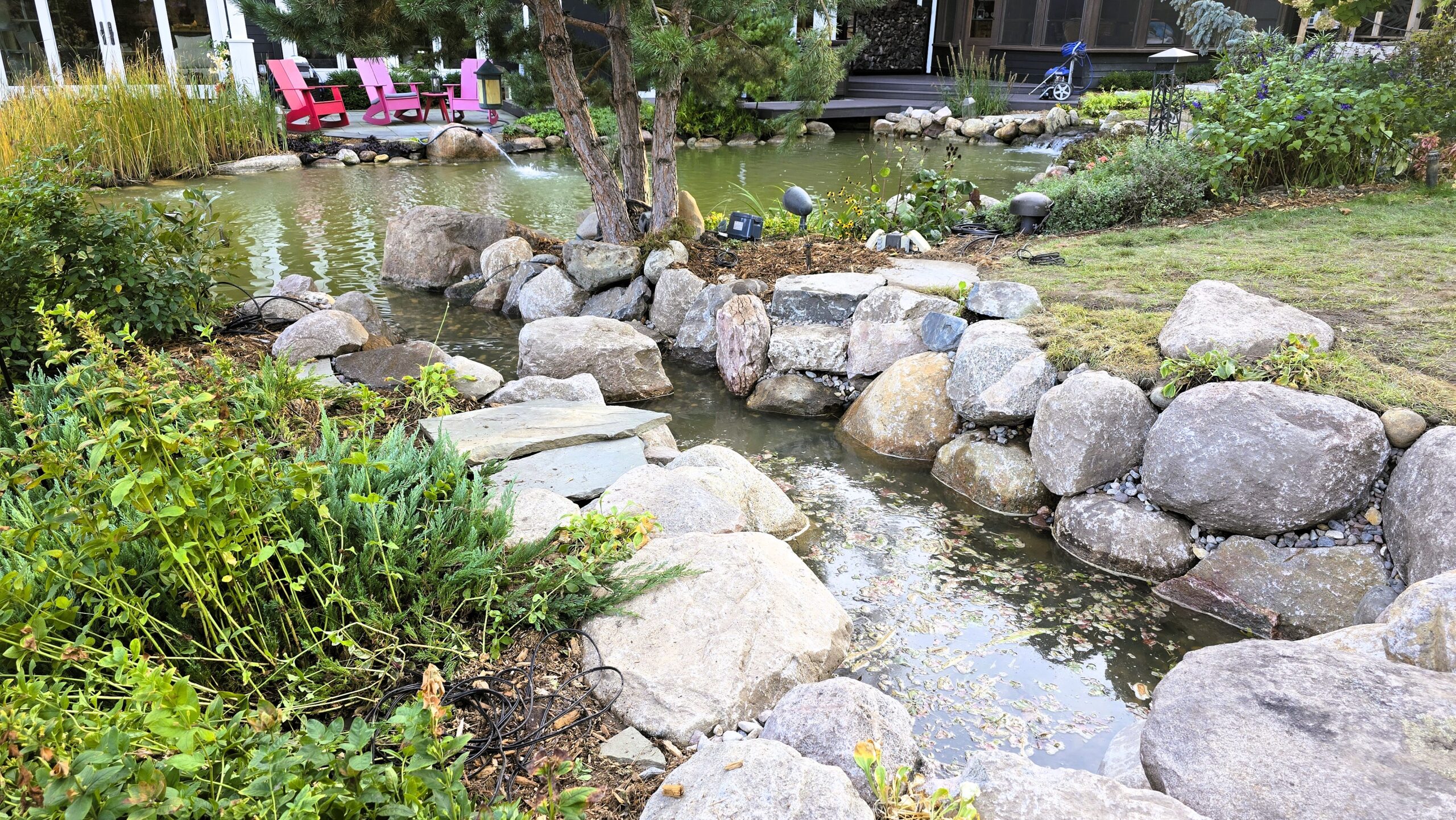 Finished intake bay integrated into large swimming pond with natural stone edge, improving debris collection and reducing skimmer maintenance in Orono, Minnesota