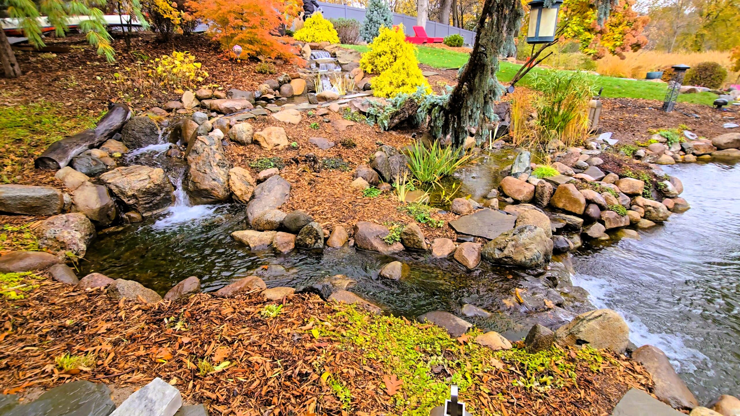 Finished intake bay integrated into large swimming pond with natural stone edge, improving debris collection and reducing skimmer maintenance in Orono, Minnesota