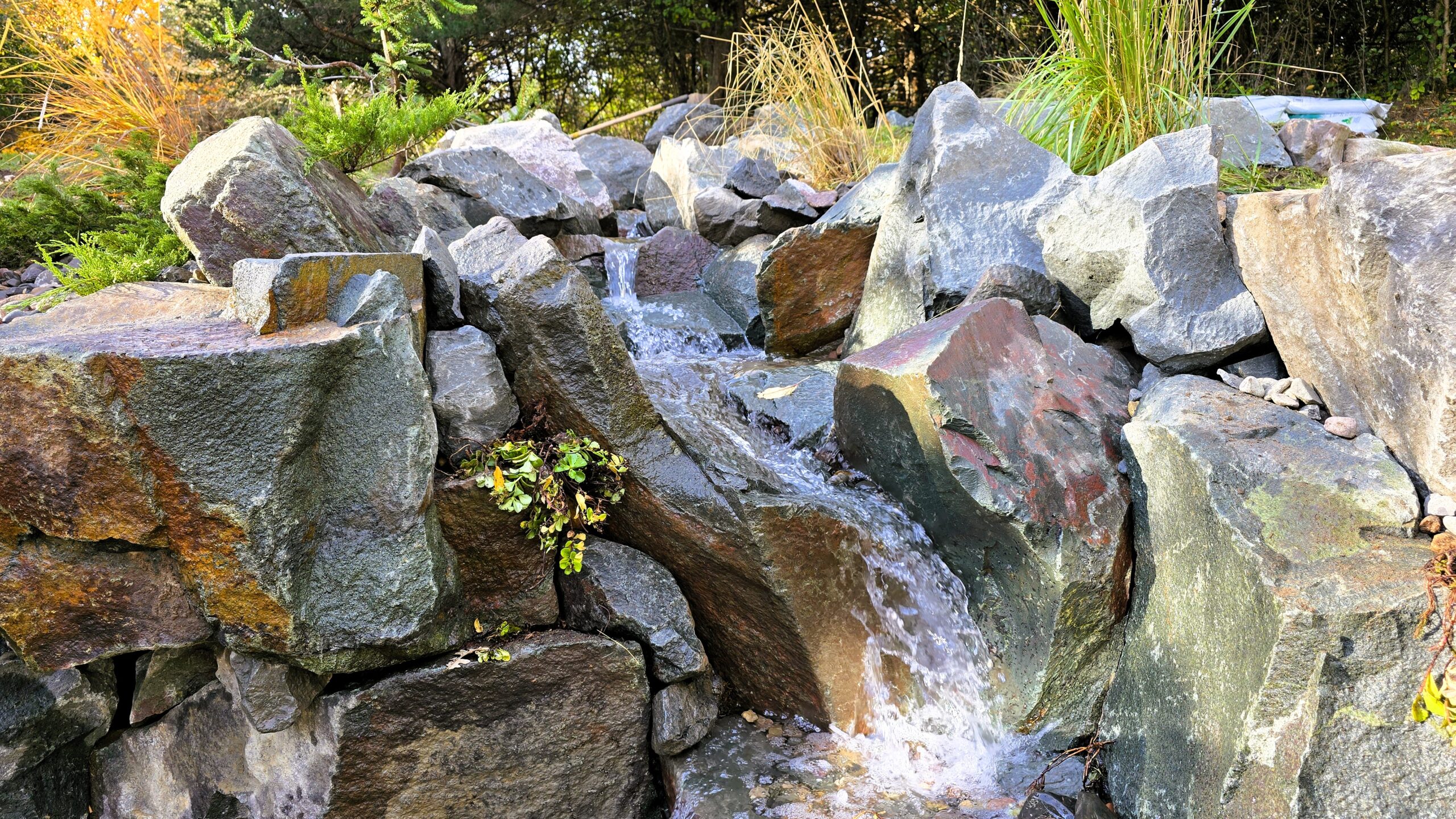 Water flowing over large natural boulders in a pondless waterfall system in Ramsey, Minnesota