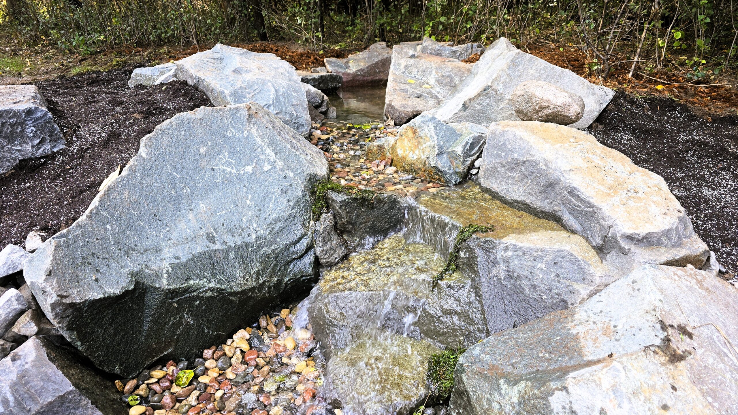 Upper waterfall section with large natural boulders and integrated wetland filter in Ramsey, Minnesota