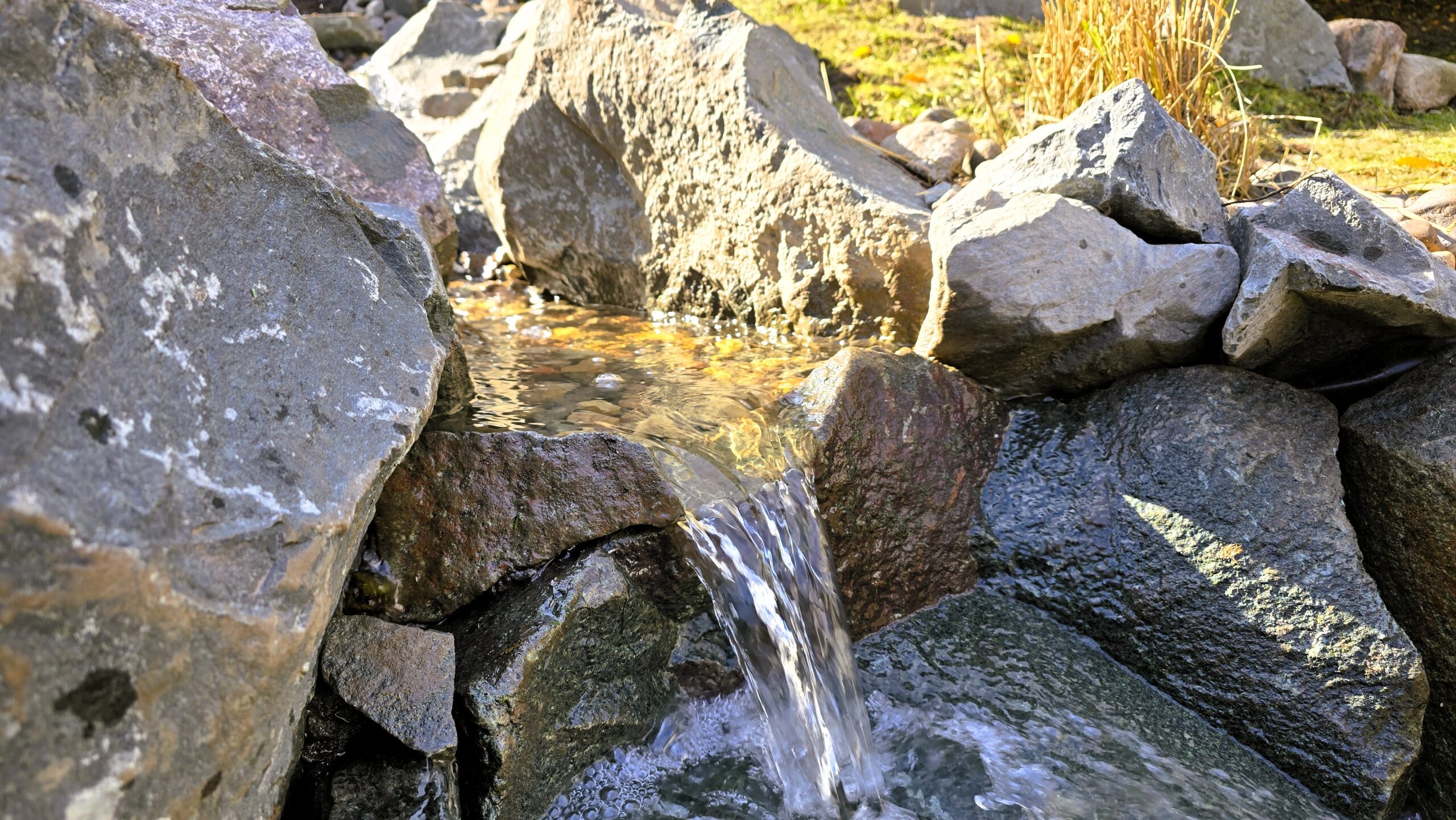 Water flowing through a natural stone cascade in a pondless waterfall and stream system in Ramsey, Minnesota