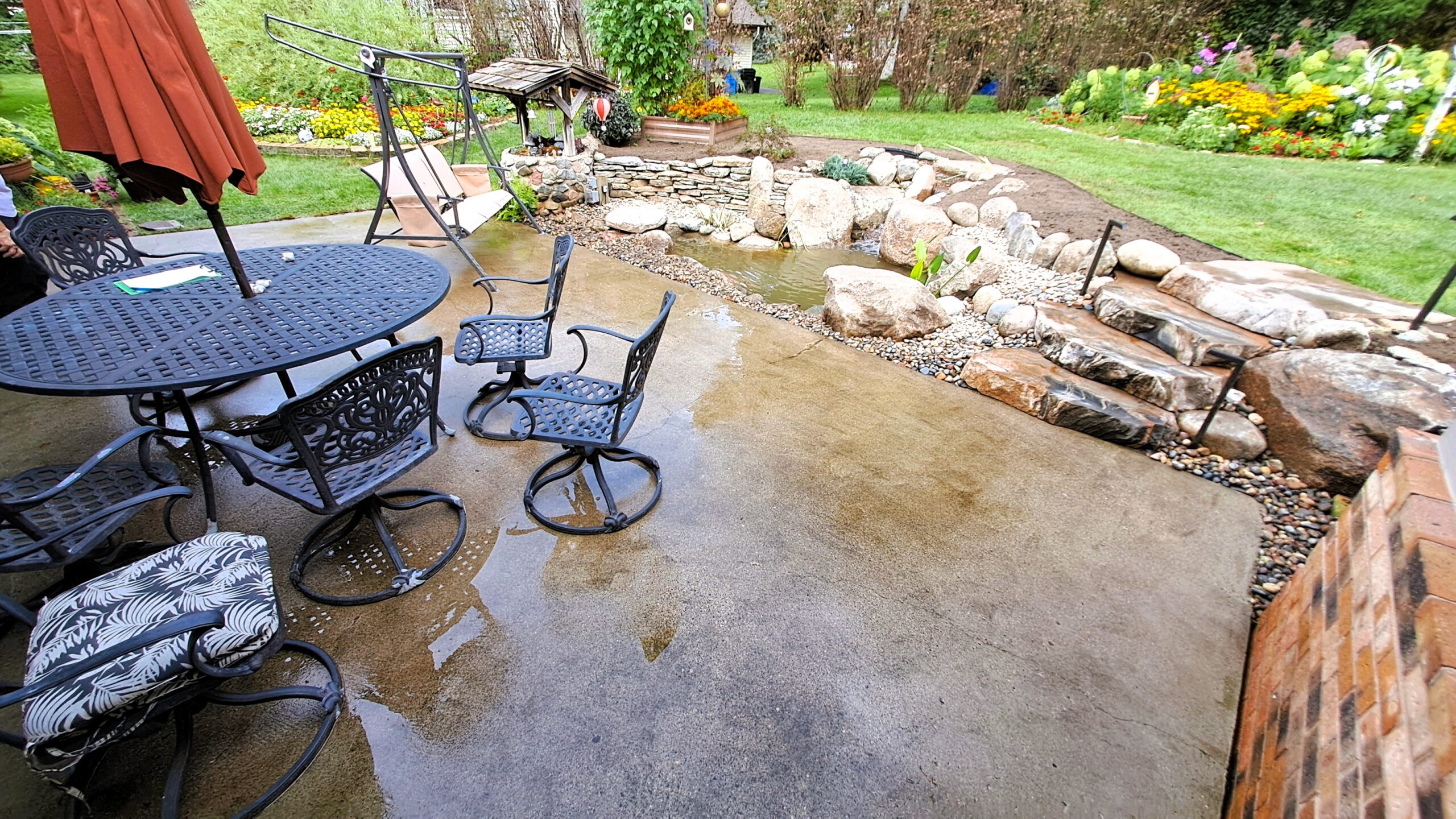 Backyard patio overlooking a renovated fish pond with waterfall and natural stone landscaping in St. Michael, Minnesota