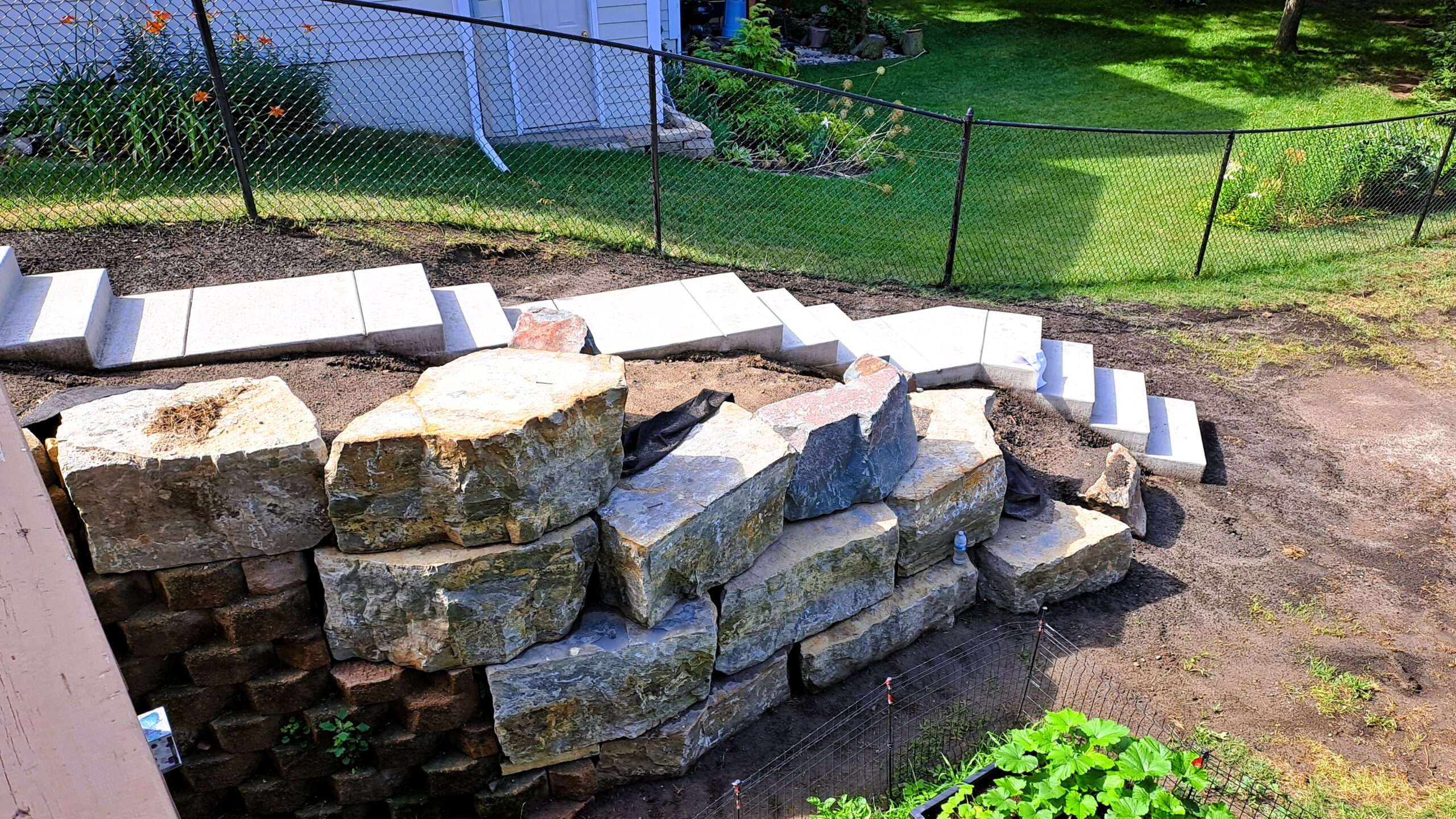 Limestone retaining wall and patio construction during a backyard pond project in Northfield, MN.