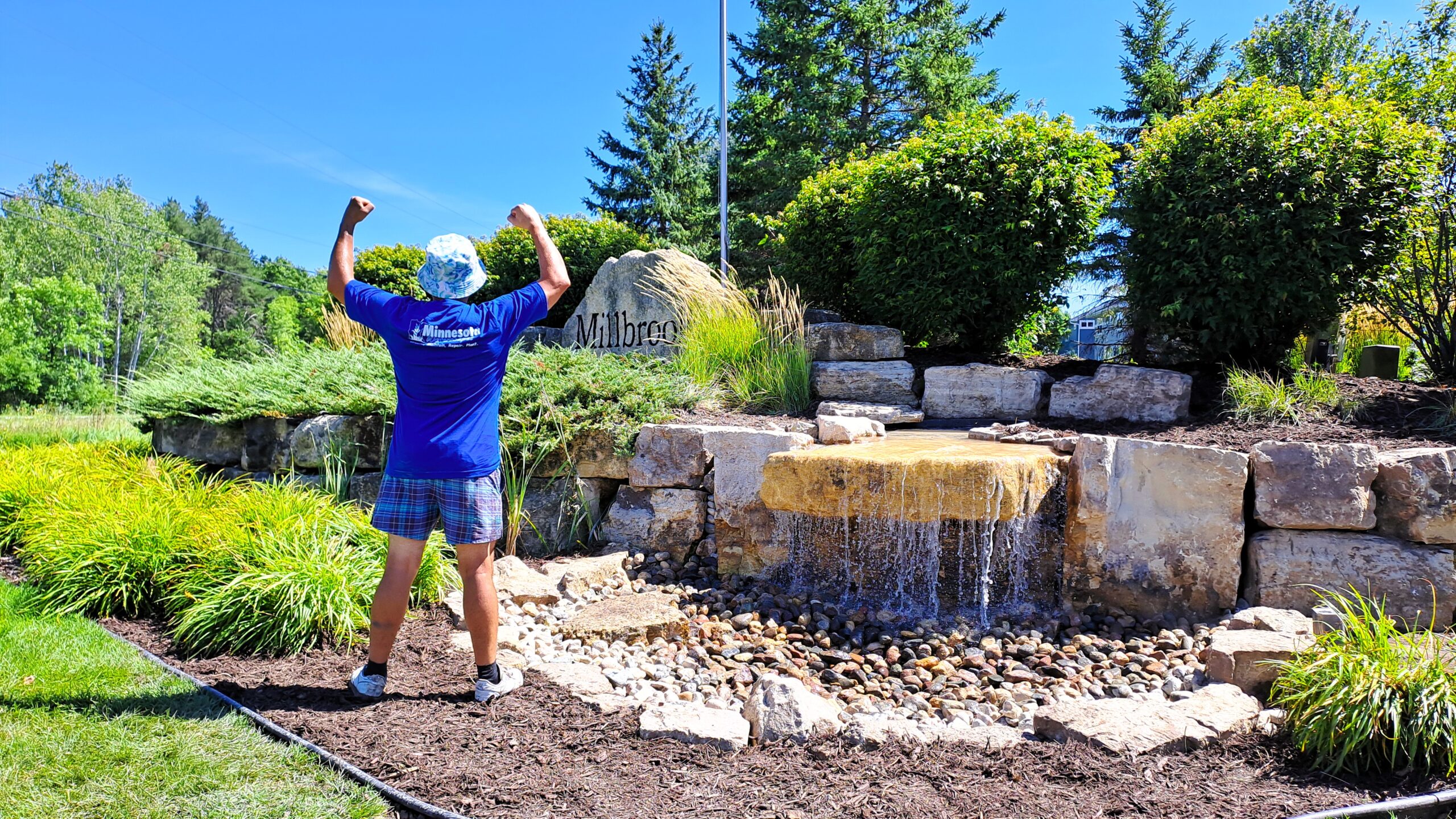 Large pondless entrance waterfall in Millbrook, MN with a 13,000 GPH sheet waterfall, community entrance sign, and natural limestone landscaping.