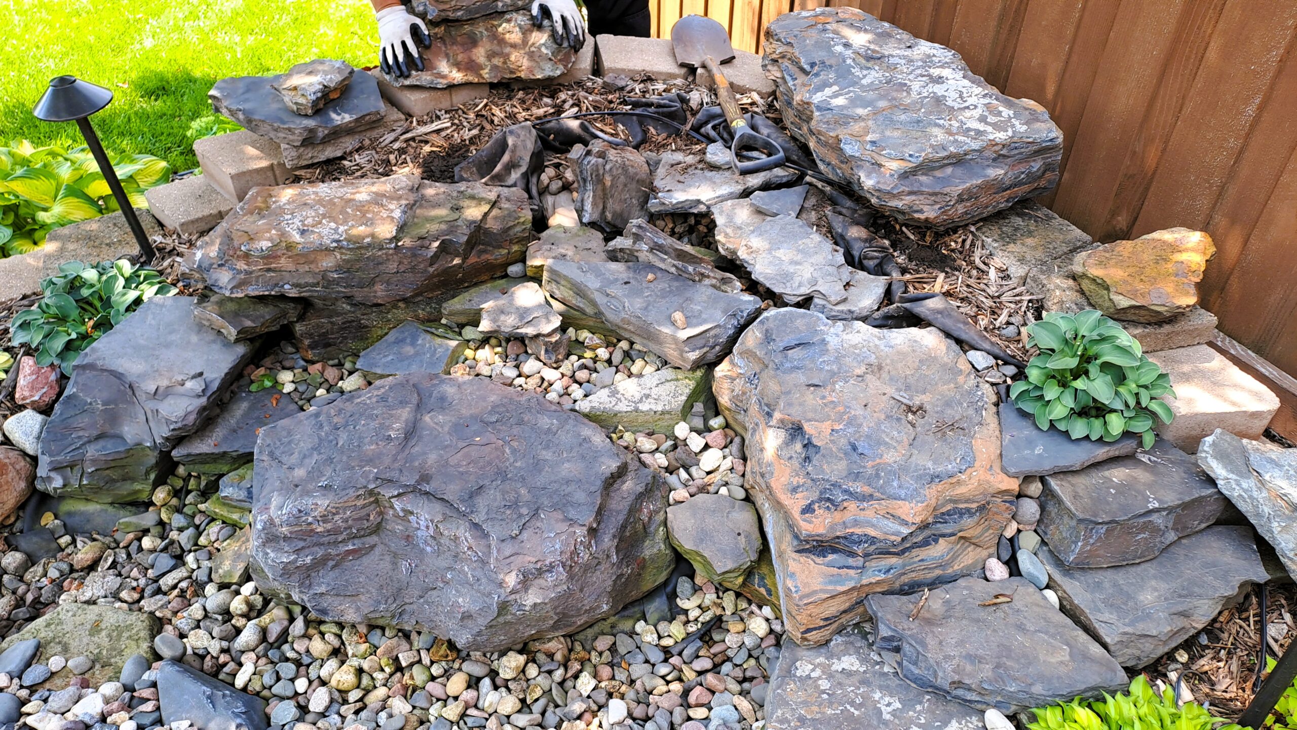Construction of a compact pondless waterfall using large Banded Jasper boulders before completion in Mendota Heights, MN.