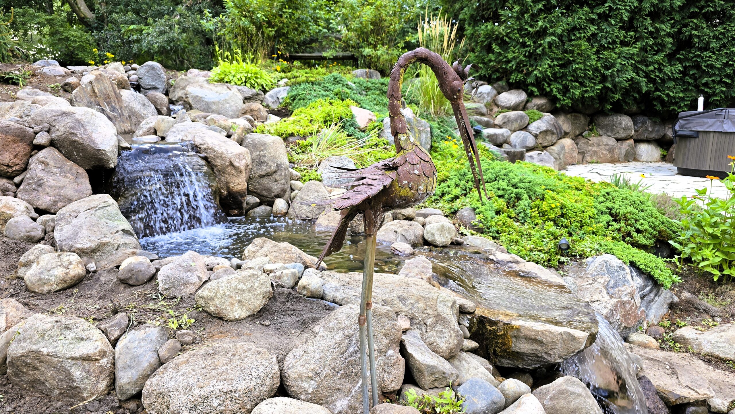 Multiple natural stone waterfalls in a rebuilt backyard stream with landscaped surroundings in Elk River, Minnesota.